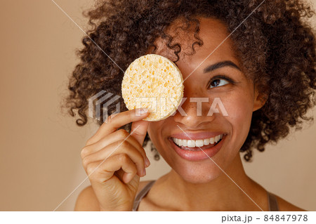 Multiethnic female showing dry sponge with toothy smile in studio Multiethnic female showing dry sponge with toothy smile in studio 84847978