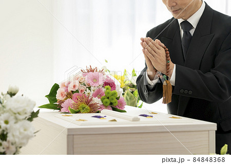 棺の前で合掌する数珠を持った男性の手元 84848368