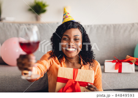 Black Woman Celebrating Birthday Toasting To Camera Holding Gift Indoor 84849593