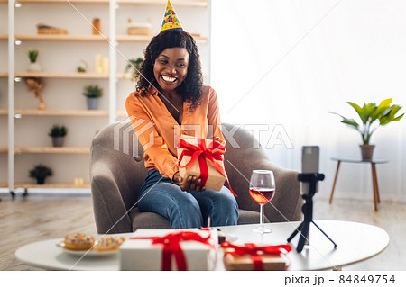 African Female Showing Gift To Smartphone Celebrating Birthday Online Indoors African Female Showing Gift To Smartphone Celebrating Birthday Online Indoors 84849754