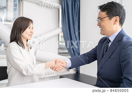 オフィスで握手をする男女のビジネスマン 84850005