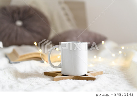 Mug mockup on a beige knited background with opened book and christmas garland lights, cozy winter day at hugge home Mug mockup on a beige knited background with opened book and christmas garland lights, cozy winter day at hugge home 84851143