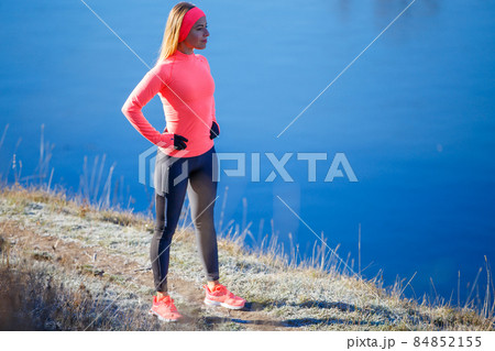 Young slim fitness woman resting near lake after her jogging in the frosty morning. Young slim fitness woman resting near lake after her jogging in the frosty morning. 84852155