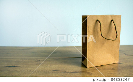 Disposable bag of kraft paper on a wooden table. Beautiful white background, copy space. 84853247