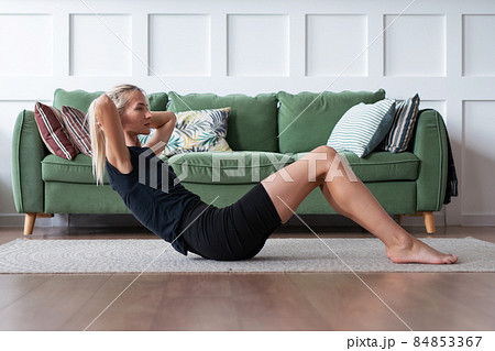 Fitness woman doing sit ups. Fit woman exercising at home lying on floor doing abs workout 84853367