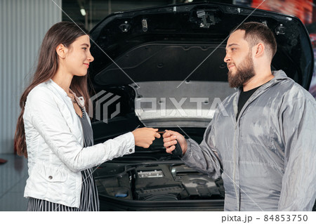 Man giving client keys to her repaired car in auto repair service 84853750