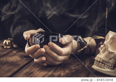 Fortune teller or oracle with holding a black cup for fortune telling on the coffee grounds. Psychic readings and the concept of clairvoyance Fortune teller or oracle with holding a black cup for fortune telling on the coffee grounds. Psychic readings and the concept of clairvoyance 84853848