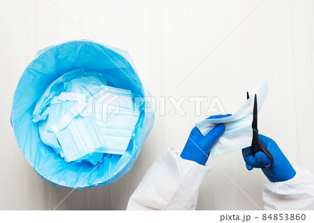Hands with scissors cut through the medical mask Hands with scissors cut through the medical mask 84853860