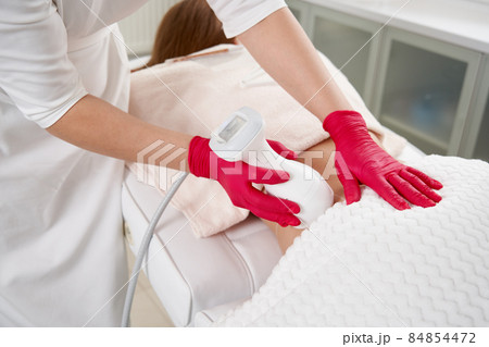 Young woman getting fat reductive skin lifting body treatment by a cosmetologist. Attractive female patient enjoying slimming body contouring procedure Young woman getting fat reductive skin lifting body treatment by a cosmetologist. Attractive female patient enjoying slimming body contouring procedure 84854472
