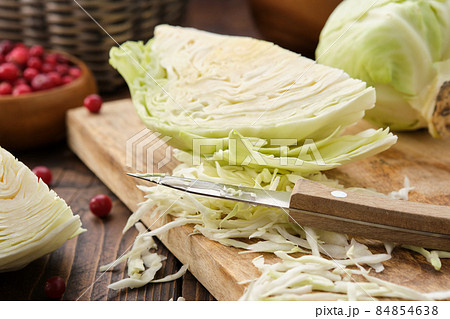 Chopped cabbage on a cutting board for making sauerkraut, coleslaw, salad or other cabbage dish. Bowl of cranberries on background. Chopped cabbage on a cutting board for making sauerkraut, coleslaw, salad or other cabbage dish. Bowl of cranberries on background. 84854638