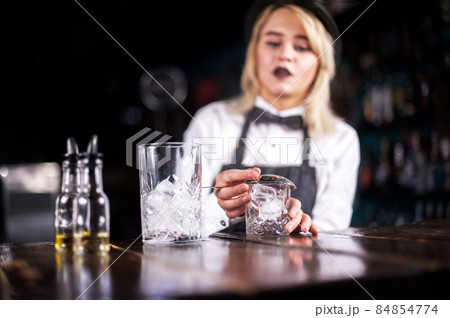 Girl barman formulates a cocktail in the taproom 84854774