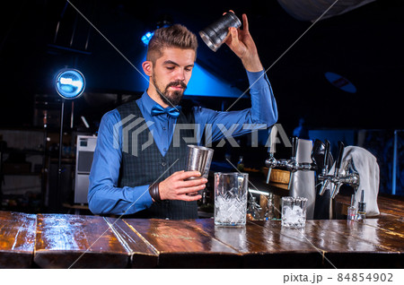 Expert Female bartender pouring fresh alcoholic drink into the glasses in the nightclub 84854902