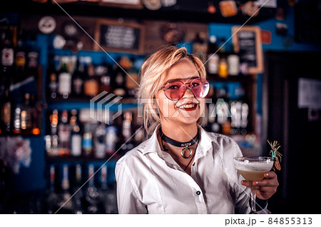 Sweet woman bartending decorates colorful concoction in the pub Sweet woman bartending decorates colorful concoction in the pub 84855313