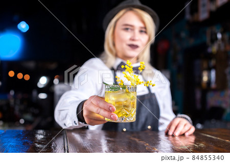 Charming girl mixologist decorates colorful concoction behind bar 84855340