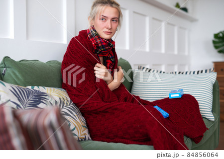 A woman with a cold sits on the sofa at home 84856064