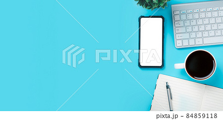 Office desk with computer, Blank screen smart phone, Notebook, pen, Cup of coffee on blue background, Top view with copy space, Mock up.. Office desk with computer, Blank screen smart phone, Notebook, pen, Cup of coffee on blue background, Top view with copy space, Mock up.. 84859118