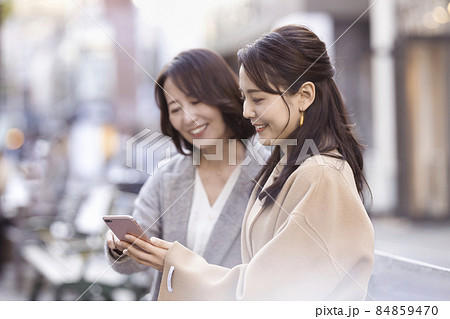 コートを着てスマホを見る2人の女性 84859470