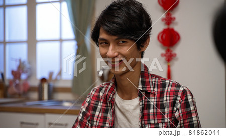 closeup of a scheming son man plaid shirt looking around at his components with cunning smile on face in mahjong game on chinese lunar new year's eve at home 84862044