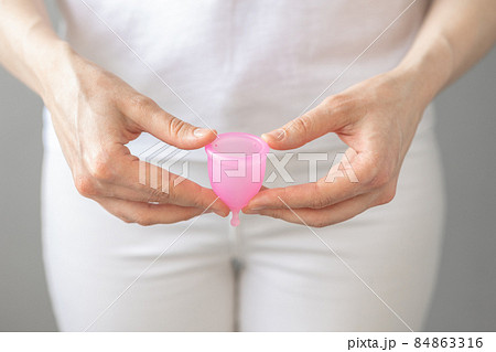 a European woman holds a pink menstrual cup made of silicone in her hands 84863316