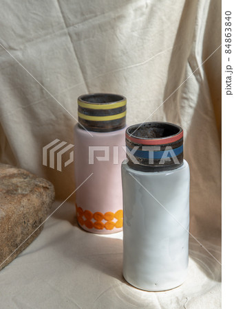Two Pink and White handmade ceramic vases on white textured table cloth. Two Pink and White handmade ceramic vases on white textured table cloth. 84863840