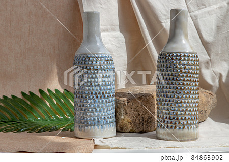 Two white and blue handmade ceramic vases on white textured table cloth. Two white and blue handmade ceramic vases on white textured table cloth. 84863902