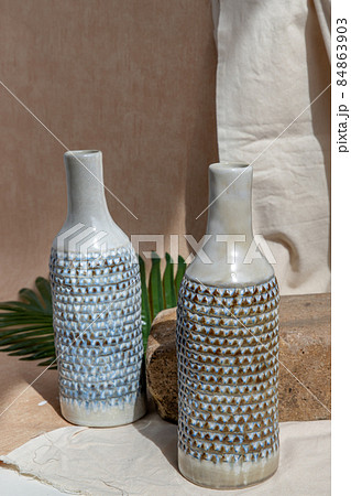 Two white and blue handmade ceramic vases on white textured table cloth. 84863903