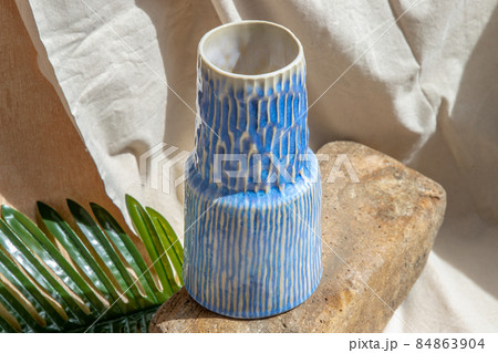 White and Blue handmade ceramic vase on white textured table cloth. 84863904