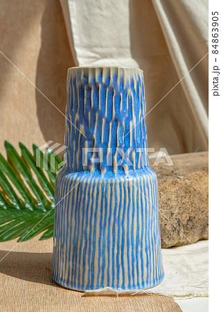 White and Blue handmade ceramic vase on white textured table cloth. White and Blue handmade ceramic vase on white textured table cloth. 84863905
