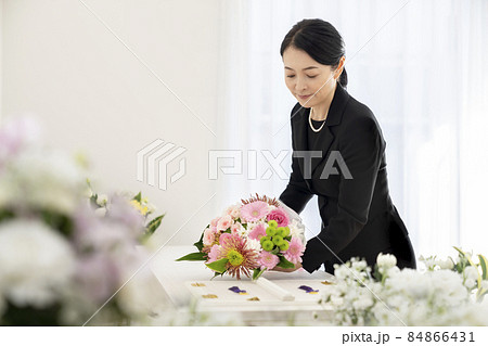 棺上花束を供えるミドルの女性 84866431