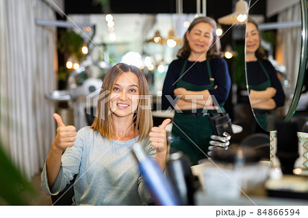 Young woman giving thumbs up happy with hairdo in hairdressing salon 84866594