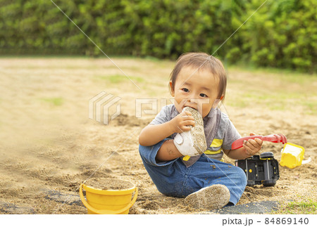 砂場で遊びながら 自分の履いている靴に噛みつく男の子 汚れた靴を口に入れるの写真素材 砂場で遊びながら 自分の履いている靴に噛みつく男の子 汚れた靴を口に入れるの写真素材