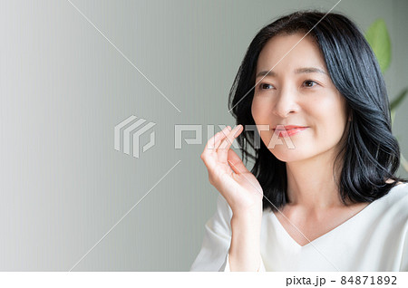 お肌の調子を気にして目を閉じる美しいアジア人 日本人 女性 クローズアップ コピースペースありの写真素材