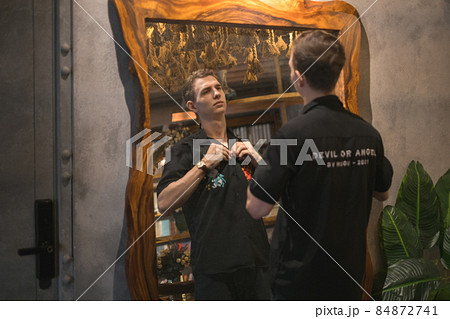 Portrait of young caucasian man in black polo standing in cafe and looking at the mirror. High quality photo 84872741