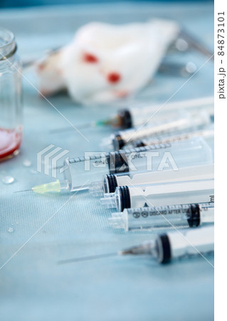 Many syringes on a blue sheet in operation room. Different sizes of syringes ready to be used Many syringes on a blue sheet in operation room. Different sizes of syringes ready to be used 84873101