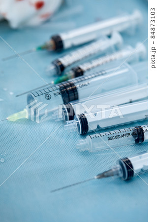 Many syringes on a blue sheet in operation room. Different sizes of syringes ready to be used Many syringes on a blue sheet in operation room. Different sizes of syringes ready to be used 84873103