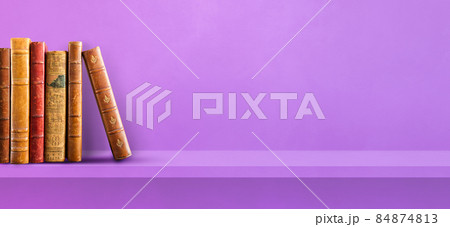 Row of old books on purple shelf. Background banner Row of old books on purple shelf. Background banner 84874813