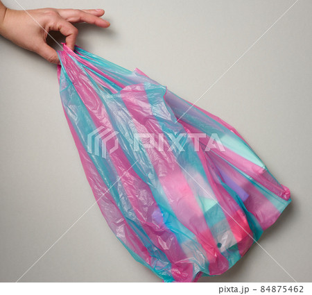 female hand holds full plastic bag on gray background, top view 84875462
