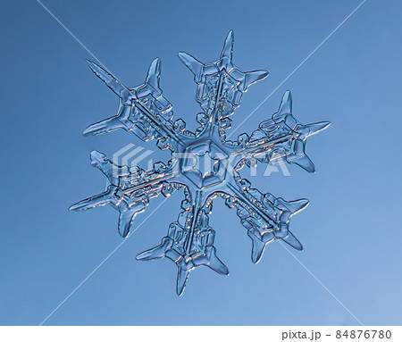 Snowflake on smooth gradient background. Macro photo of real snow crystal on glass surface. This is small snowflake with unusual pattern. 84876780