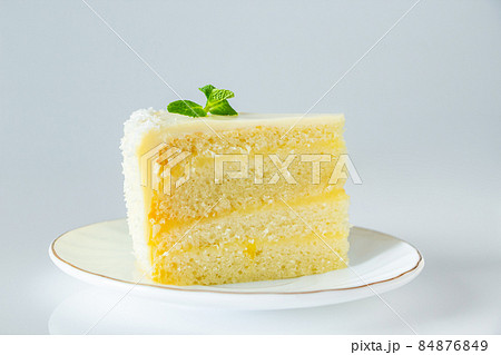 Lemon cake with coconut flakes. A piece of delicate vanilla dessert with cream. 84876849