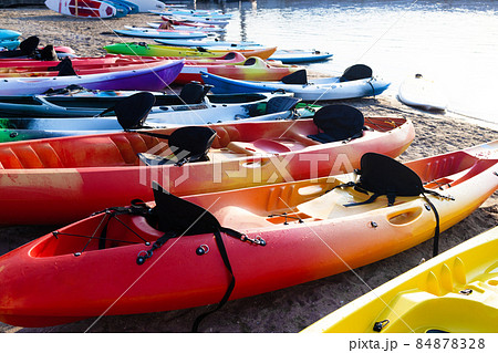 Colorful plactic kayaks or canoe on the beach sand for tourist rent. Surfing boards on stand during summer season 84878328