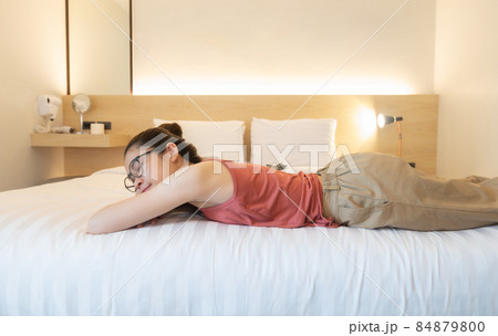 Young Asian woman sleeping on comfortable bed in cozy style hotel bedroom. Sleep is essential for strong health and well-being. Young Asian woman sleeping on comfortable bed in cozy style hotel bedroom. Sleep is essential for strong health and well-being. 84879800