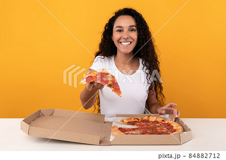 Happy Latin Lady Holding Pizza Offering Slice To Camera 84882712