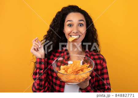 Excited Latin Lady Eating Delicious Potato Crisps Excited Latin Lady Eating Delicious Potato Crisps 84882771