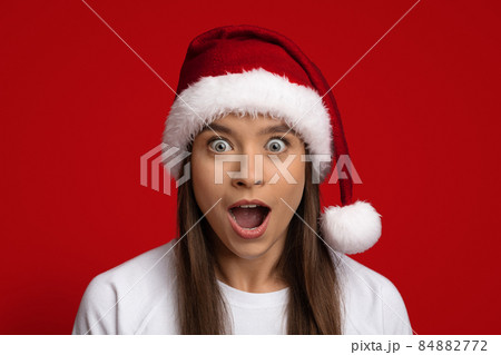 Amazing Offer. Portrait Of Shocked Woman Wearing Santa Hat Looking At Camera Amazing Offer. Portrait Of Shocked Woman Wearing Santa Hat Looking At Camera 84882772