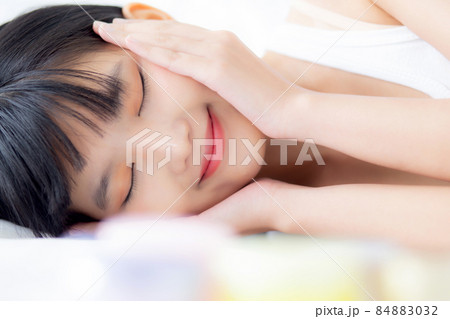 Beautiful of young asian woman smiling and lying on bed at bedroom, beauty of girl touch cheek. 84883032