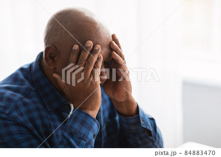 Mature African Man Suffering From Headache Touching Head Sitting Indoors 84883470