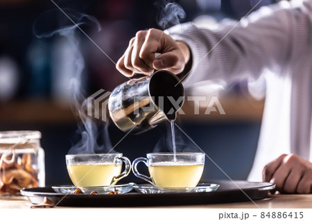 The bartender pours hot mulled wine or a winter whiskey drink Hot Teddy The bartender pours hot mulled wine or a winter whiskey drink Hot Teddy 84886415