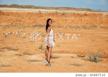 beautiful tanned woman in a summer dress in a clay desert 84887510