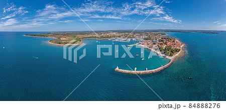Drone panorama over the Croatian coastal town Novigrad with harbor and promenade taken from the sea side during the day 84888276