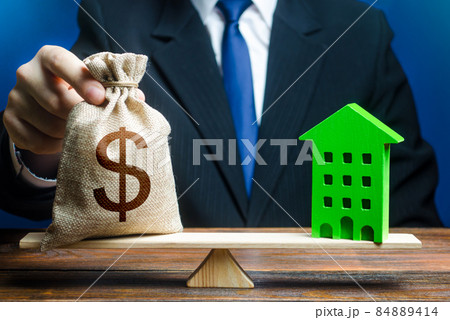 Businessman puts dollar money bag on scales and green house. Profitability housing of eco technologies. Investment in renovation. Reduced CO2 emissions, energy efficiency. Payback period 84889414